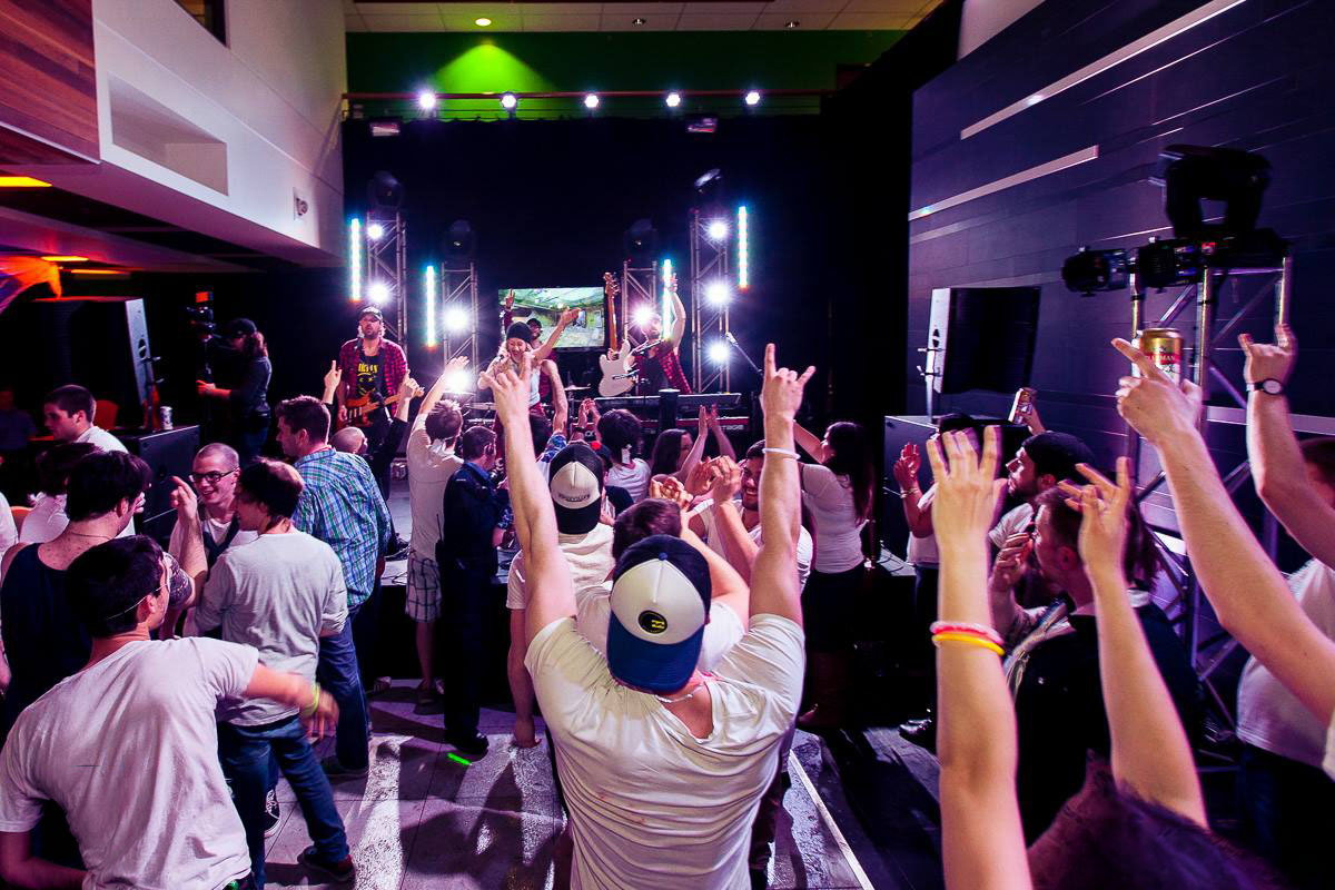 Live band performing in a modern indoor venue with vertical light bars and a crowd with raised hands